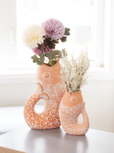 The Gurgling Fish Vase by ABBOTT comes in 2 sizes and is crafted out of ceramic in terracotta with etched detailing accented in white. The large size measures 11.5 inches high.