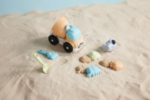 The Truck Beach Toy Set by Mud Pie is a 7-piece recycled wheat straw plastic set and includes a truck, four sand molds, rake and shovel.